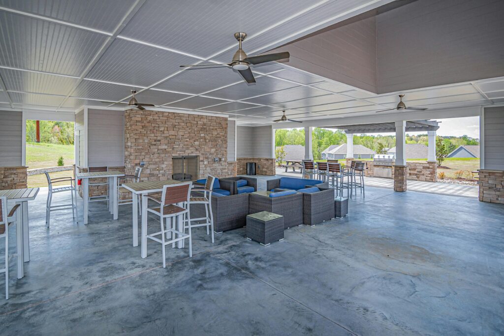 Spacious outdoor patio area featuring modern furniture and a stone fireplace, perfect for relaxation.
