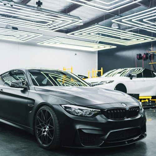 A sleek black luxury car parked in a modern garage with striking lighting design.