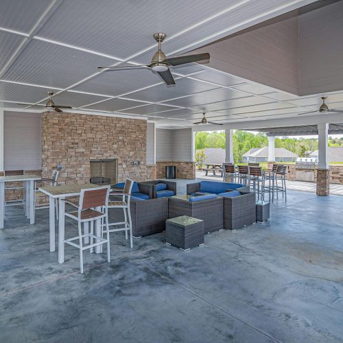 Spacious outdoor patio area featuring modern furniture and a stone fireplace, perfect for relaxation.
